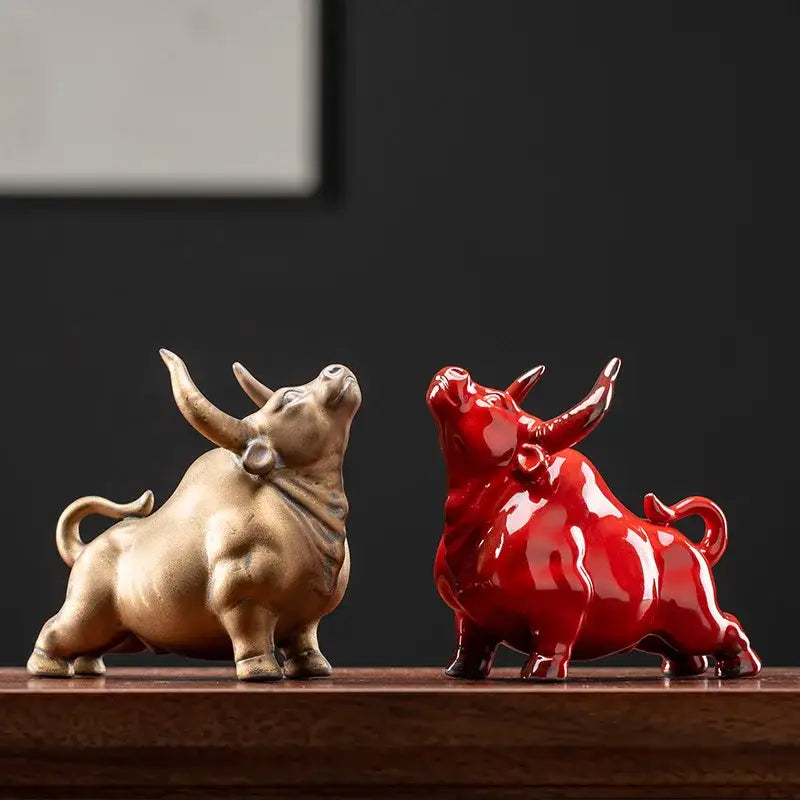 Two ceramic bull figurines in metallic gold and glossy red finishes for office decor from decorbites bull figurine collection