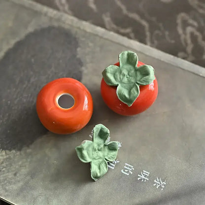 Glossy orange ceramic persimmon fruit sculpture tea caddy with green leaf accents for kitchen decor