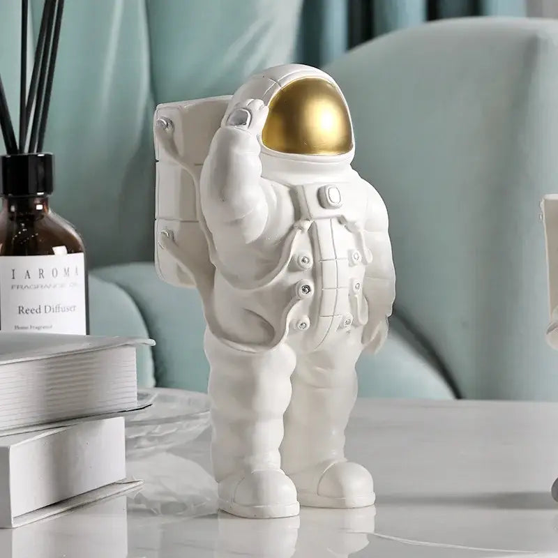 Glossy white and gold astronaut phone holder figurine with a gold helmet standing on a table for bedroom decor
