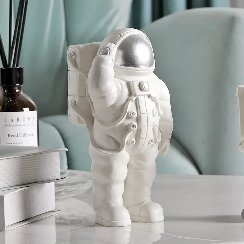 Glossy white and gold astronaut phone holder with metallic silver helmet and detailed suit standing on a table