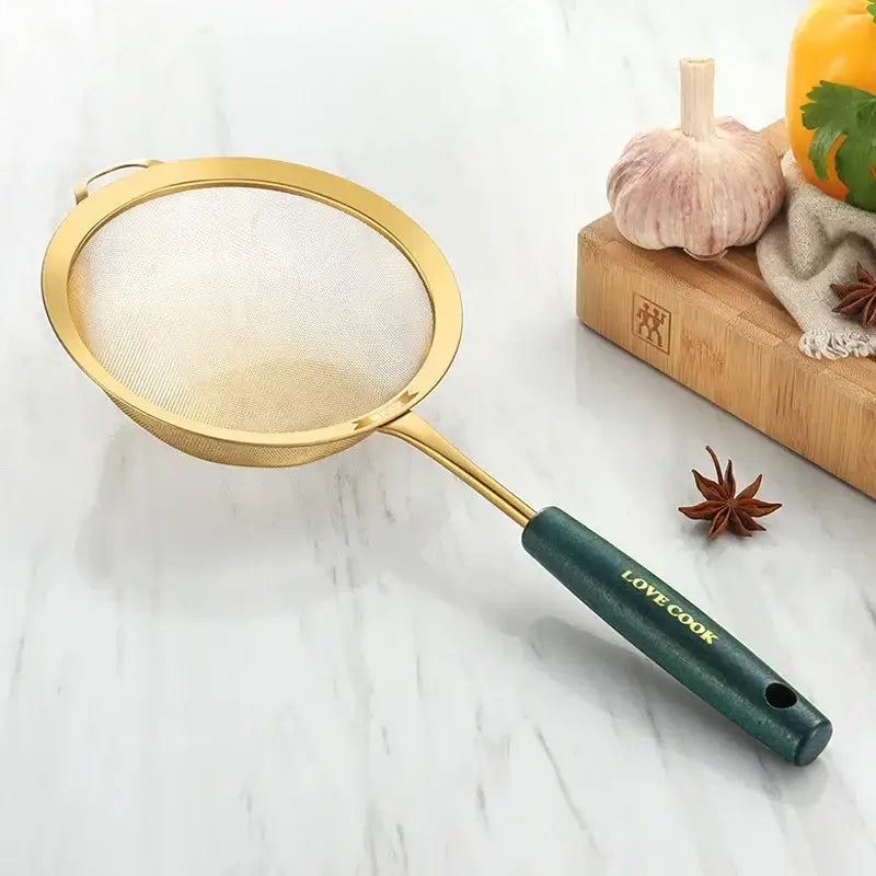 Gold-colored metal kitchen colander juice strainer with dark green handle engraved love cook by decorbites kitchen colander