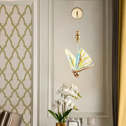 Gold and patterned butterfly led wall light with iridescent yellow blue wings suspended by gold chain ceiling mount