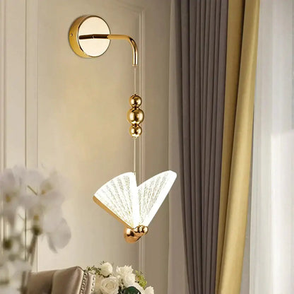Gold-finished wall light with delicate fan-shaped glass shade featuring intricate etched patterns for bedroom use