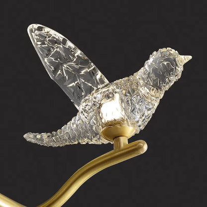 A gold bird branch led pendant lamp with clear crystal glass and a golden brass base designed for dining room use
