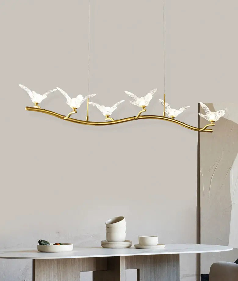 Gold-toned branch-shaped pendant lamp with five translucent white bird figures and adjustable chain cord length for dining room