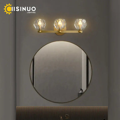 Gold-toned brass vanity light fixtures with three faceted crystal shades for bathroom use