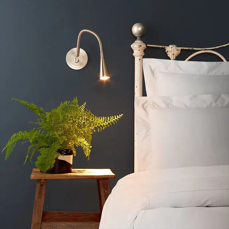 A sleek silver aluminum led gooseneck wall sconce with adjustable arm for focused bedroom reading light