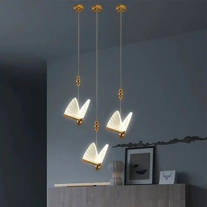Gold butterfly pendant light with acrylic elements features translucent illuminated wings as a ceiling light source