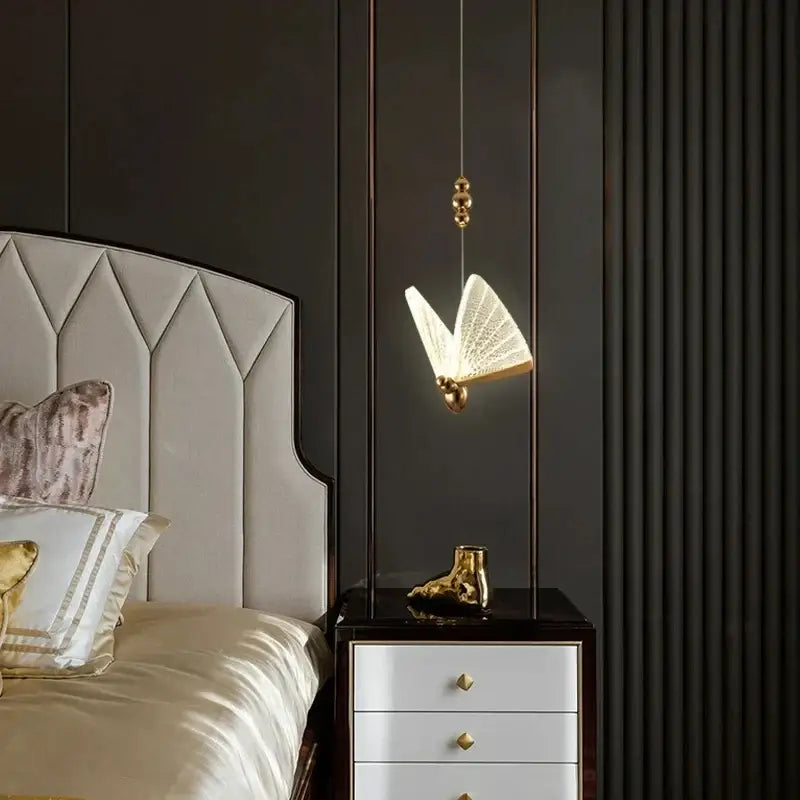Gold butterfly pendant light with acrylic elements and illuminated open-wing design works beautifully above nightstand