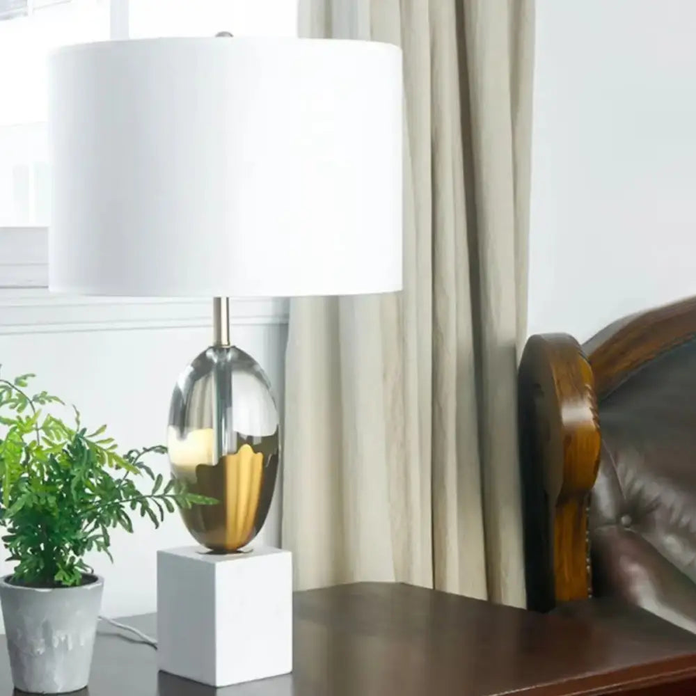 Modern fabric table lamp with a gold and silver mirrored metallic base and white crystal fabric shade for bedroom use