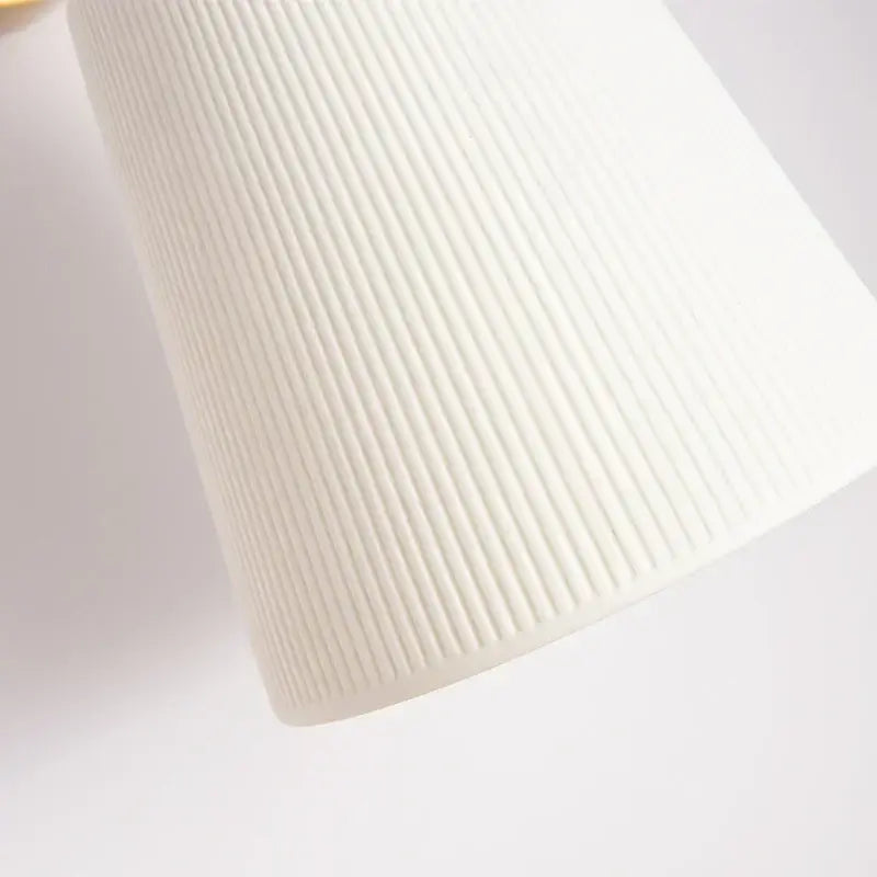 A sleek white ribbed fabric shade on a gold ceramic led wall lamp by decorbites for living room decor
