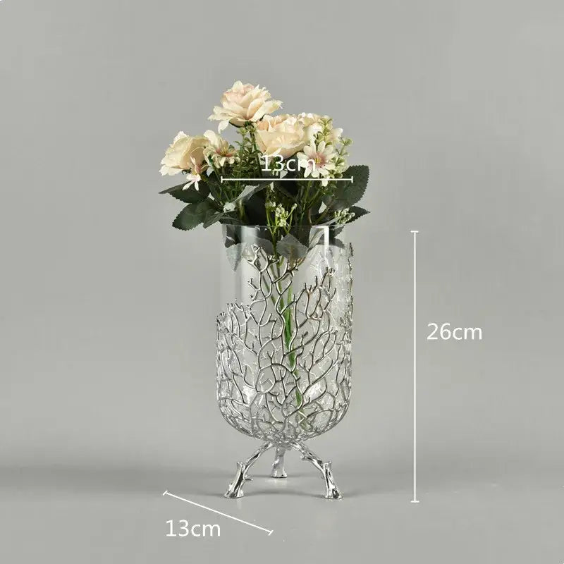 Silver metallic vase with intricate branching wire design and three-legged base holding cream roses for coral crystal tree decor