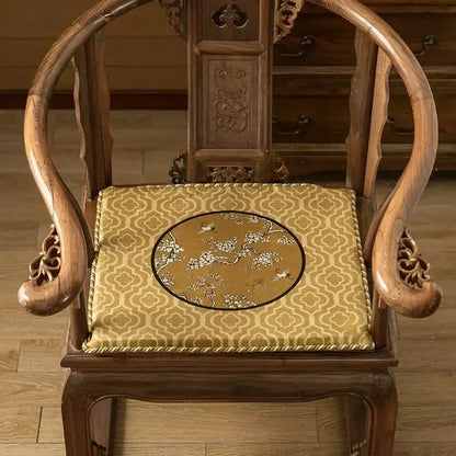 Golden-yellow lumbar pillow case with crane birds branches embroidery on dark gold background on wooden chair