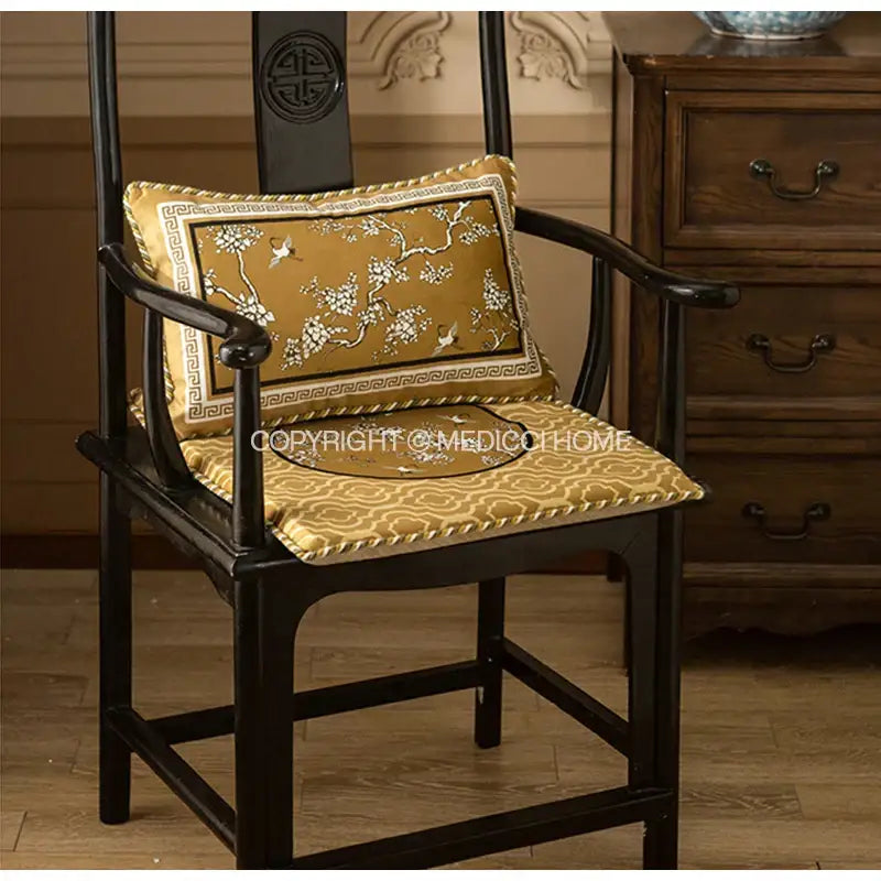 Gold embroidered lumbar pillow case with crane birds branches motifs on dark wooden chair for living room use