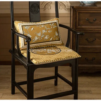 Gold embroidered lumbar pillow case with crane birds branches motifs on dark wooden chair for living room use