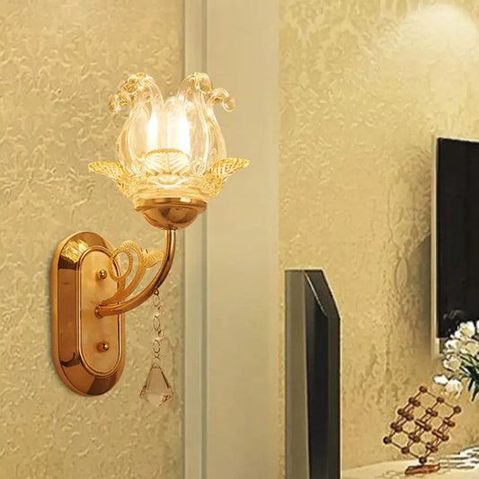 Gold-toned wall lamp with clear glass lotus-shaped shade and crystal droplet featuring simplicity blossom design and fixture width