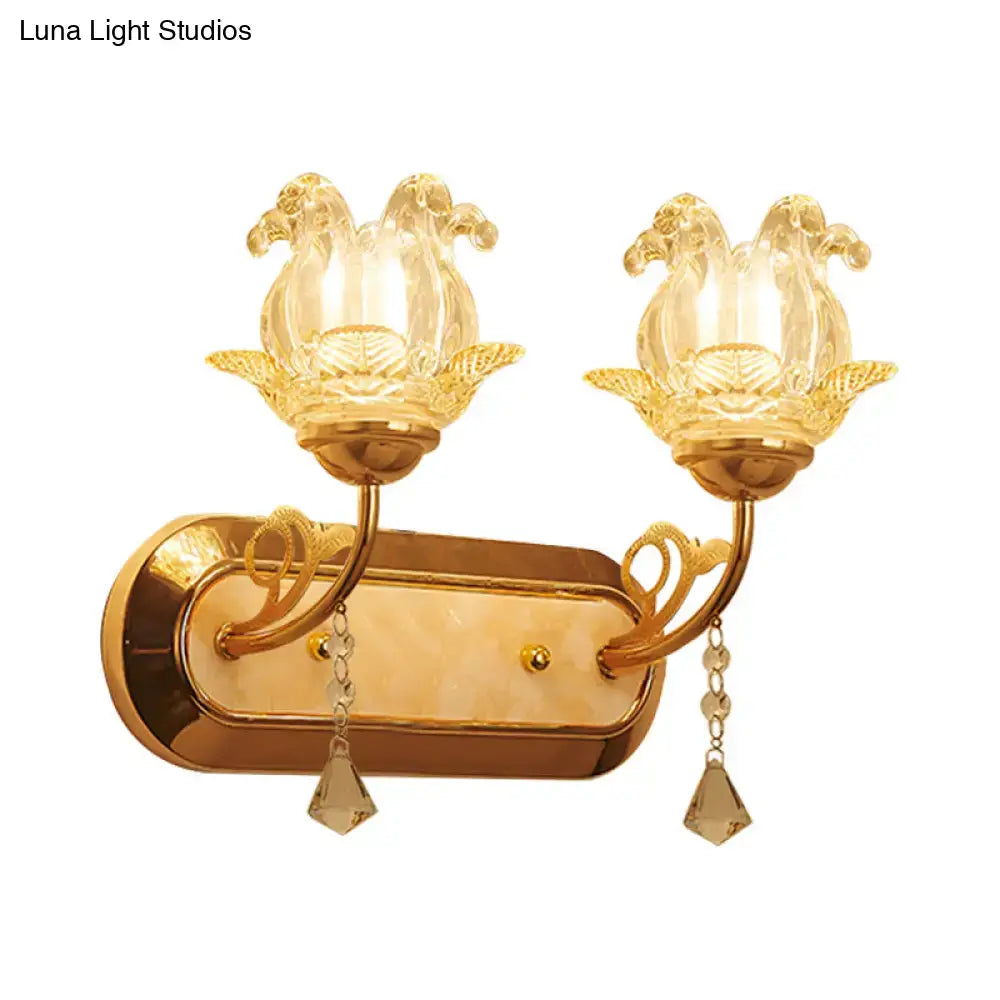 Gold wall lamp with two lotus glass lampshades and crystal teardrops featuring a simplicity blossom fixture width design