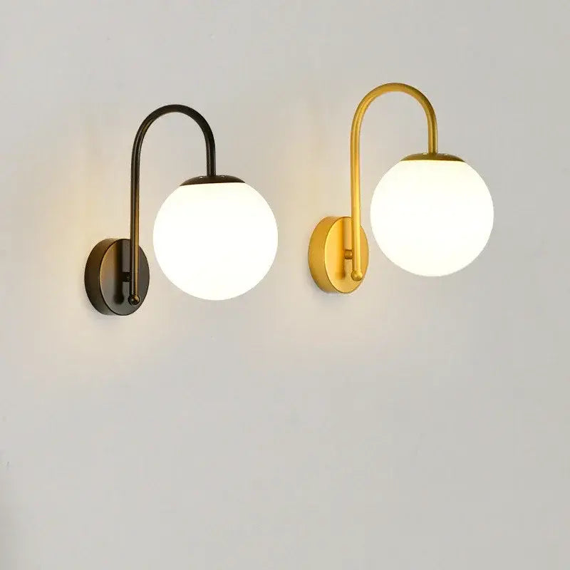 Two modern wall sconces with curved metal arms and frosted glass balls in matte black and brushed gold decorbites glass ball led design