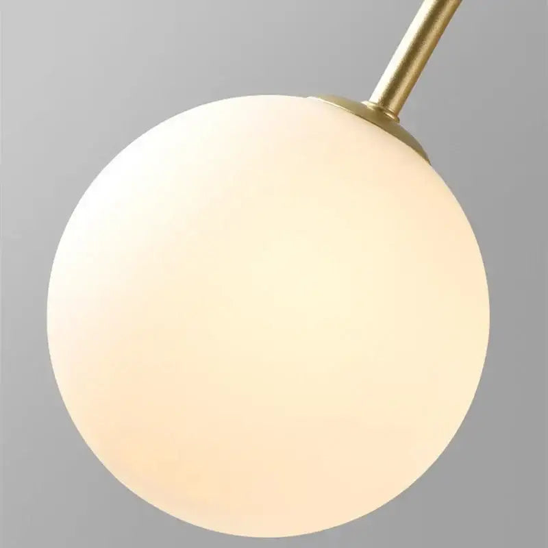 Gold curved arm glass ball pendant chandelier with a warm frosted glass globe and sleek brass stem for dining room decorbites glass ball