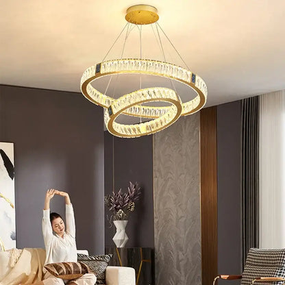 Gold-toned decorbites crystal round ceiling chandelier with clear crystal accents and modern elegant design for dining room