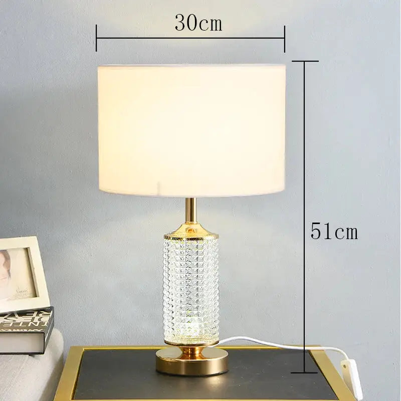 Gold faceted clear crystal glass table lamp with a gold-toned textured body and cream fabric shade for bedroom decor