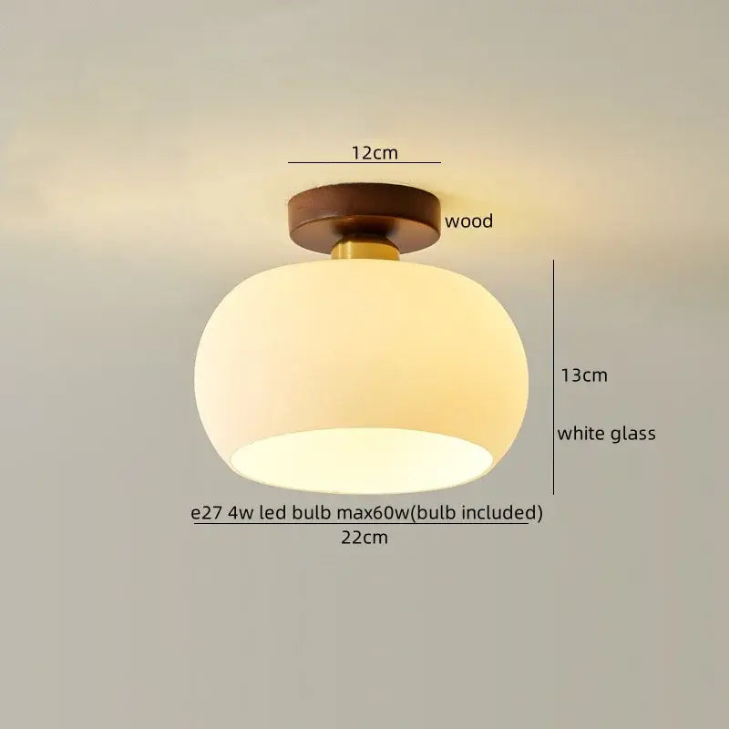 A warm softly glowing gold flower frosted glass ceiling lamp with a round white cotton shape led shade and wooden base