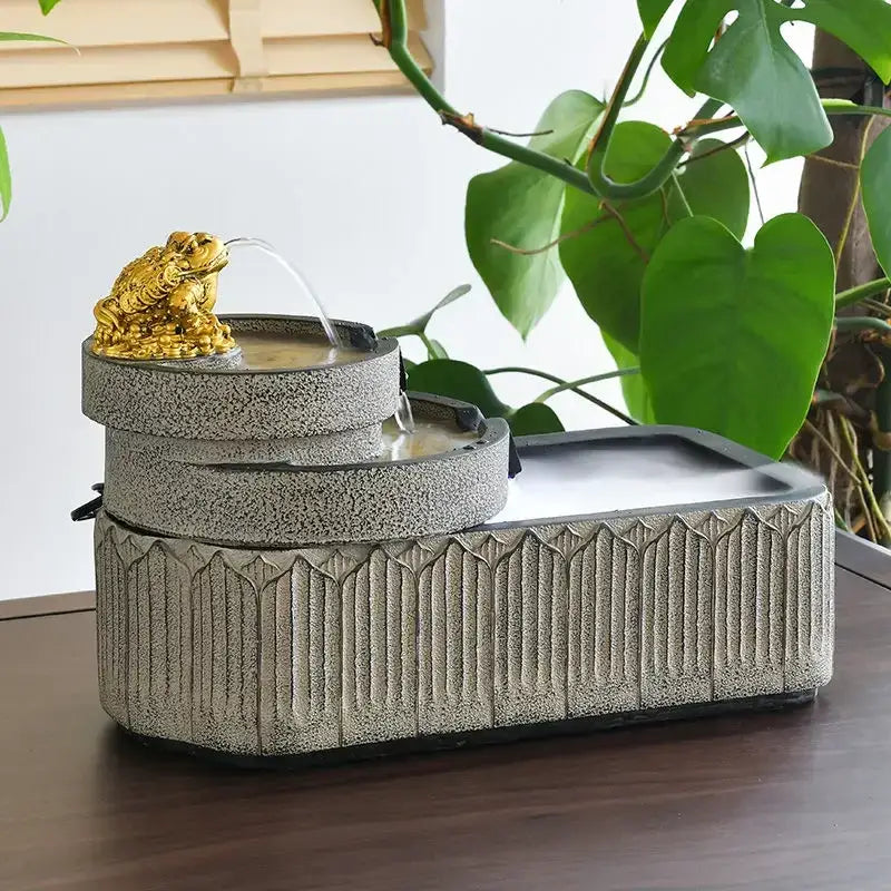 Gold-colored frog figurine on gray stone textured fountain with flowing water for fish pond tank garden ornament