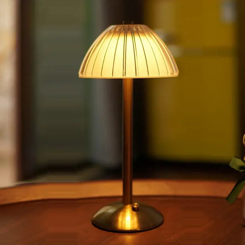 A warm-toned brass table lamp with a cream pleated glass shade featuring a diamond touch sensor led for bedroom use