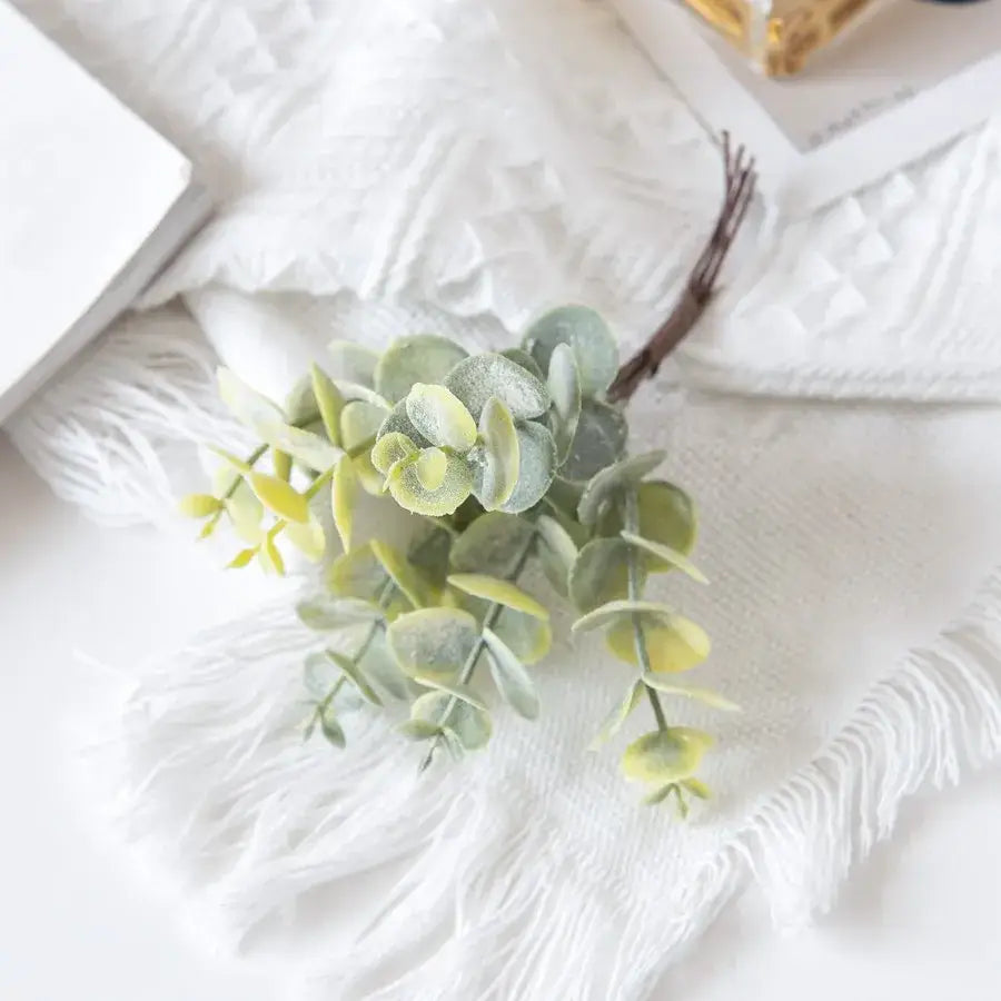 A delicate artificial eucalyptus leaves sprig in gold silver and muted green tones for wedding decor by decorbites