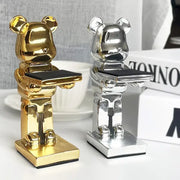 Two metallic gold and silver bear statue watch racks each holding a black tray for bedroom storage stand