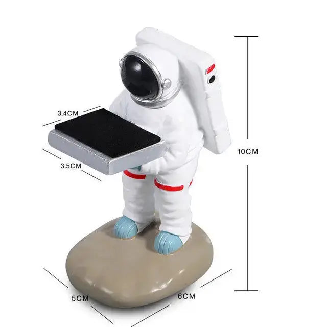 White astronaut figurine with red accents and blue boots holding tablet on beige base of bear statue watch rack