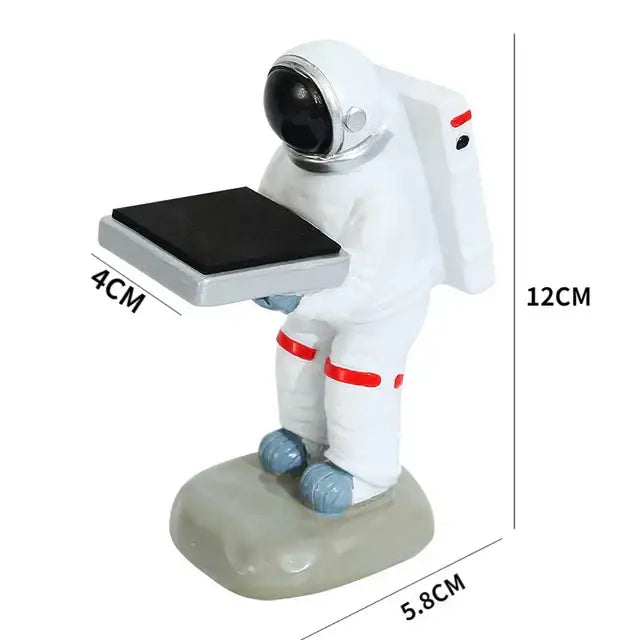 White astronaut figurine with red accents and blue boots holding black solar panel on tray for bear statue watch rack