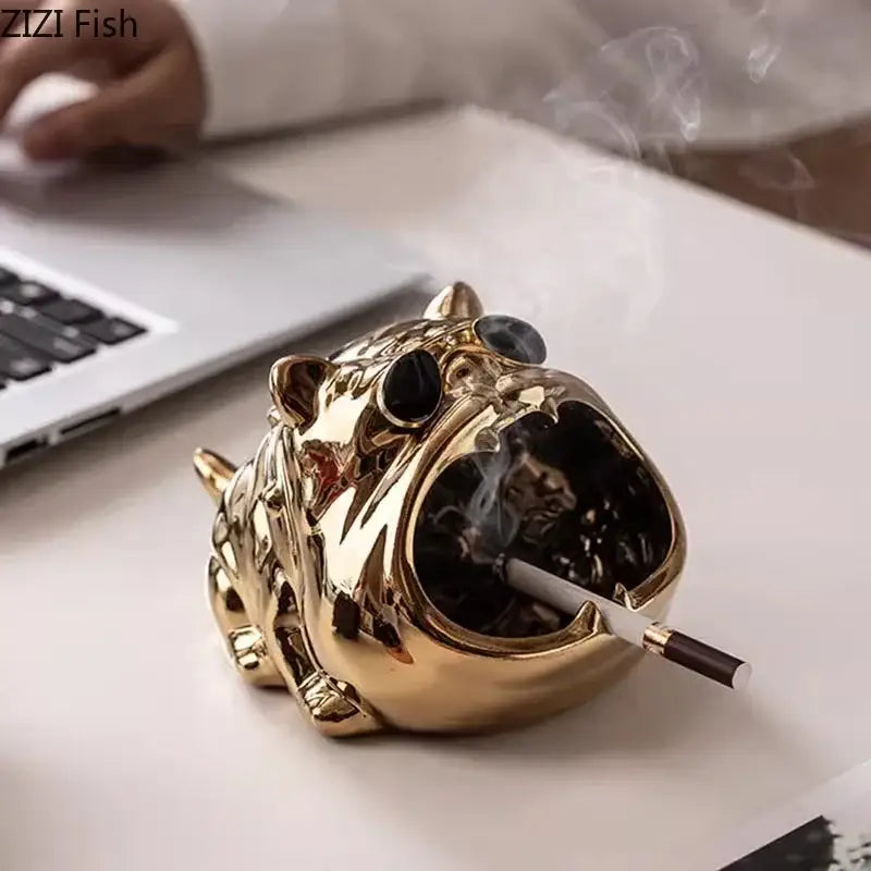 Gold and silver decorbites bulldog ceramic ashtray with black glass eyes and cigarette on office desktop decor