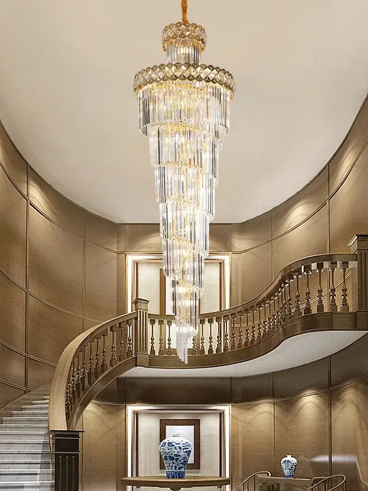 A gold stainless steel crystal chandelier with cascading clear glass prisms hanging as a staircase pendant light