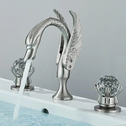 Silver swan-shaped bathroom faucet with ornate feather detailing and gold swan crystal globe handles by decorbites