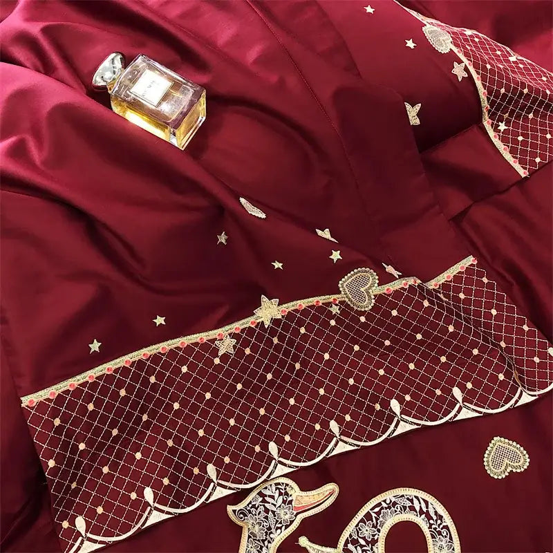 Luxurious burgundy satin comforter with gold swan love embroidery featuring star patterns and heart embellishments bedding set