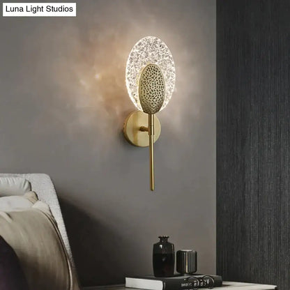 Gold-toned led wall lamp with textured oval glass shade and intricate metal backplate for indoor lighting