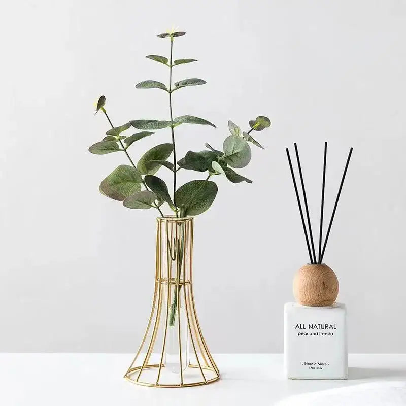 Gold vase metal wireframe holding green eucalyptus branches modern desk decoration with metal flowers element