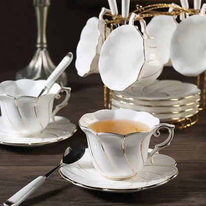 Elegant white bone china cup set with gold wave trim filled with amber tea from decorbites gold wave collection