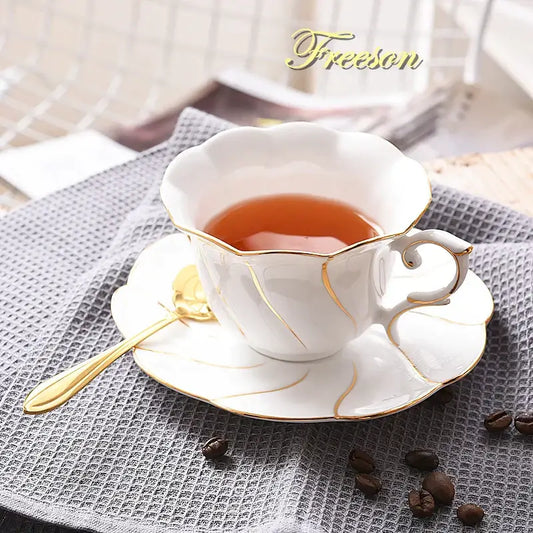 White bone china cup set with gold wave detailing filled with amber tea by decorbites gold wave collection