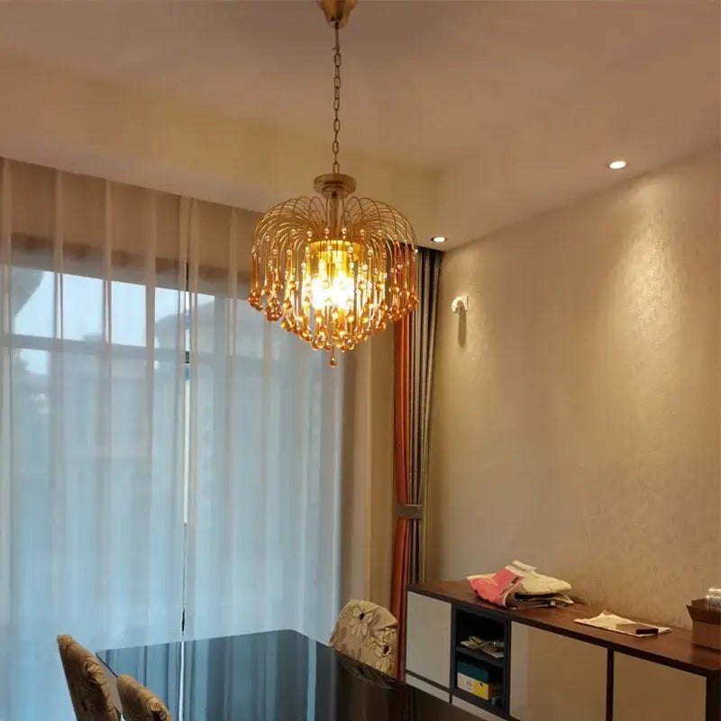 Golden amber crystal water drop chandelier with cascading droplets and warm glowing light for dining room use