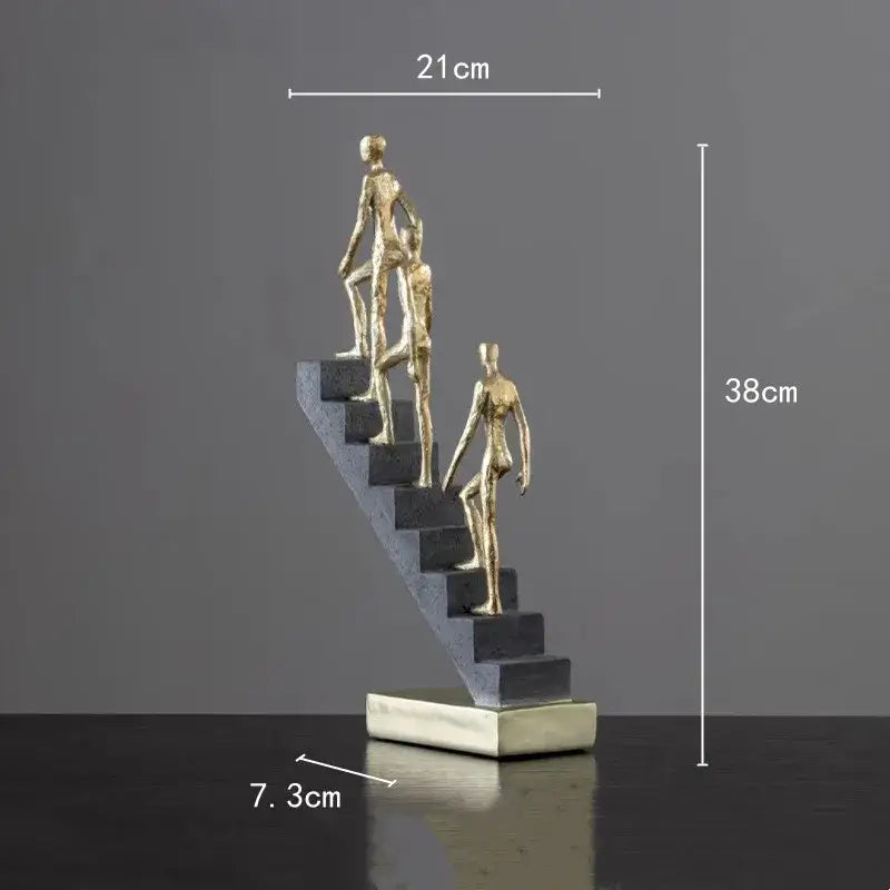 Golden man abstract resin sculpture featuring three golden figures ascending dark gray steps on a silver base decorbites golden man