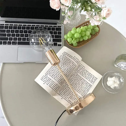 A sleek decorbites golden modern led desk lamp with clear glass bulb and gold-toned metal base for bedroom decor