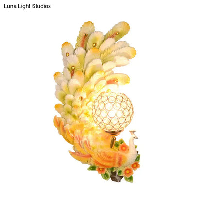 Golden peacock wall light with crystal shade featuring yellow green feathers and floral accents for living room decor