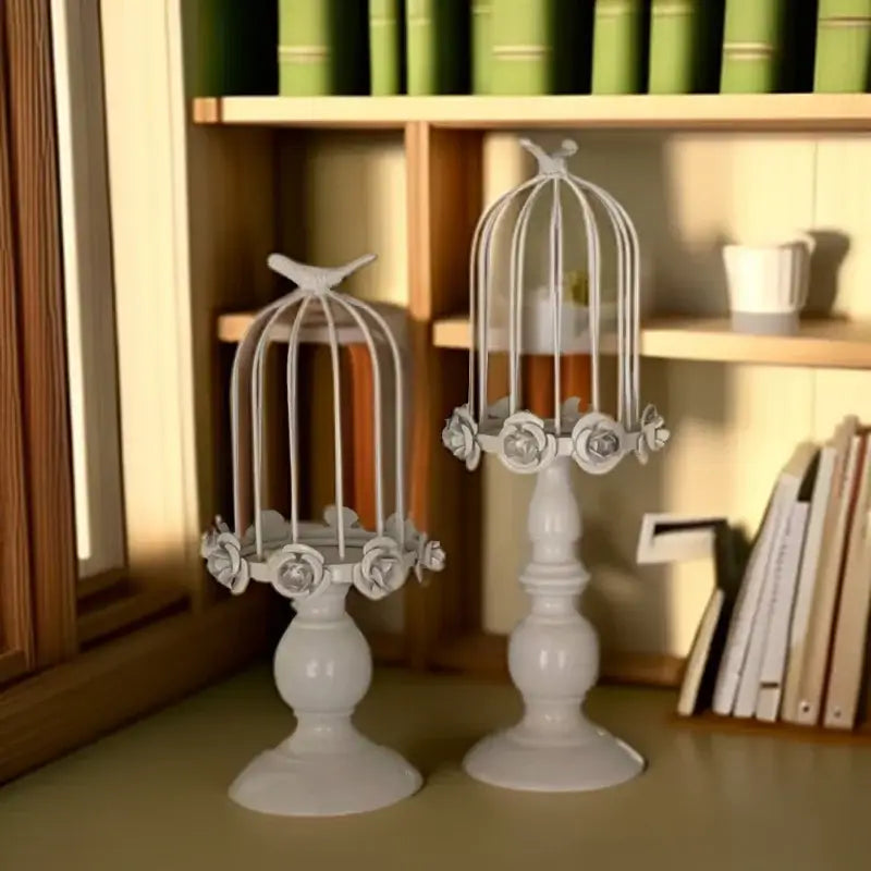 White metal birdcage style ornament candle holders with floral embellishments and ornate bases for dining room decor