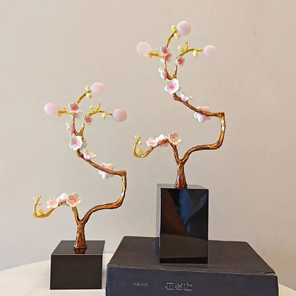 Two golden tree metal decor figurines with pink and white blossoms on black square bases for living room display