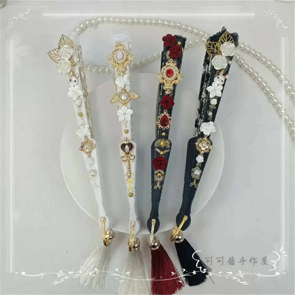 Elegant lace fan holders in white and black with gold filigree, embroidered roses, pearls, and decorbites elegant gemstone handles
