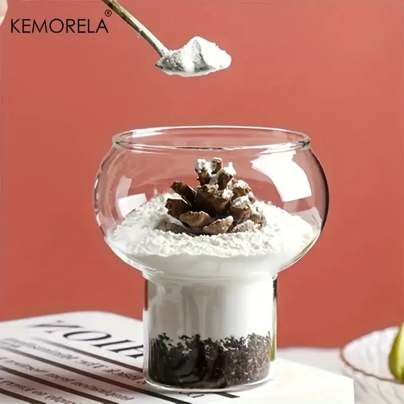 Clear glass gourd shaped glass cup with wooden handle featuring layered white sand soil and pinecone inside terrarium