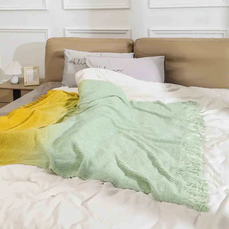 A soft knit blanket with decorbites gradient pineapple grid pattern in yellow to mint green with tasseled edges