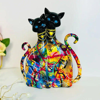 Vibrant abstract-painted ceramic decorbites cat couple sculpture with glowing blue eyes and gold-trimmed necklaces for decor